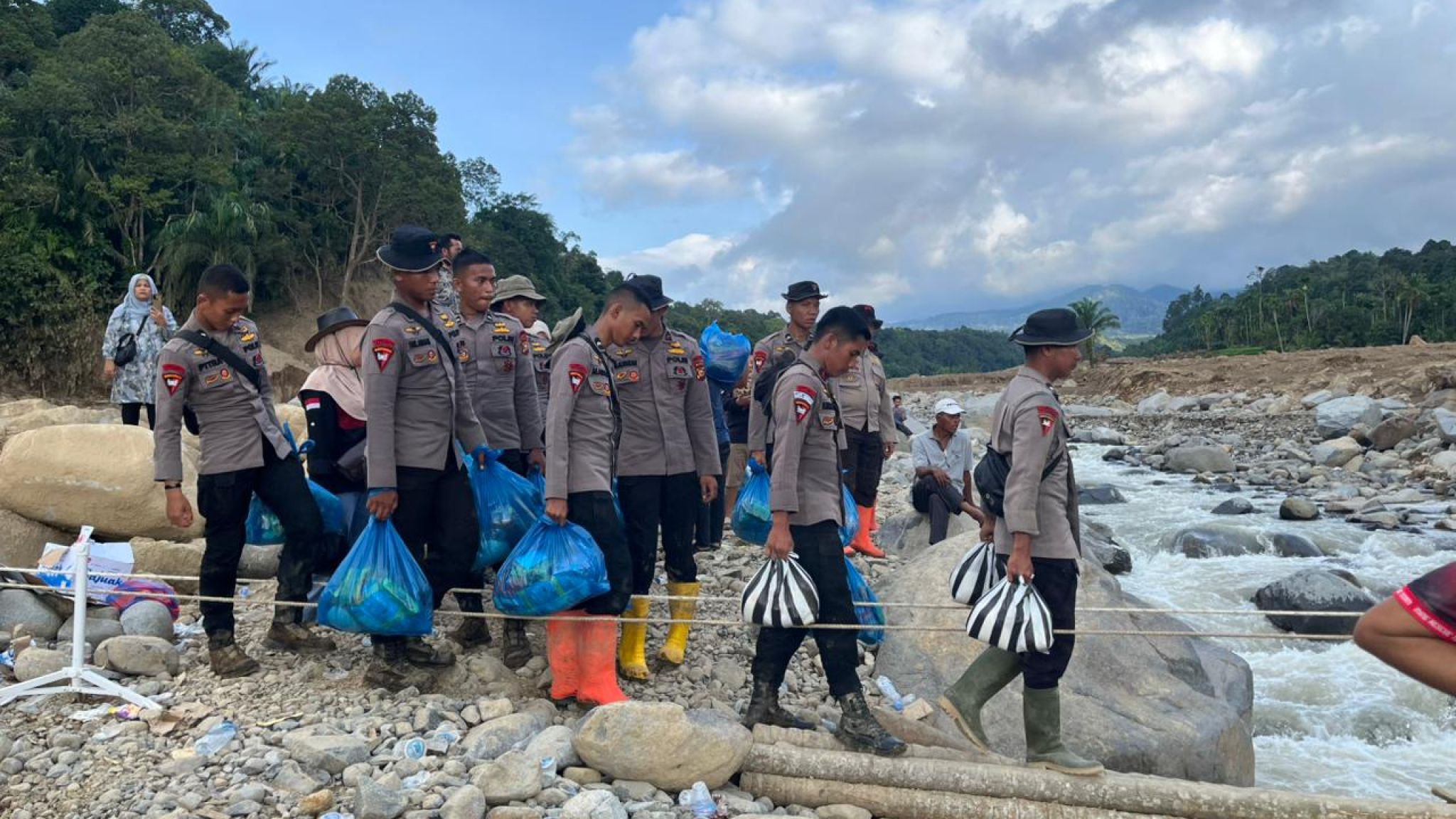 Personel Polda Riau Bantu Warga Menyebrangi Jembatan Darurat dan Evakuasi Barang Korban Bencana di Agam
